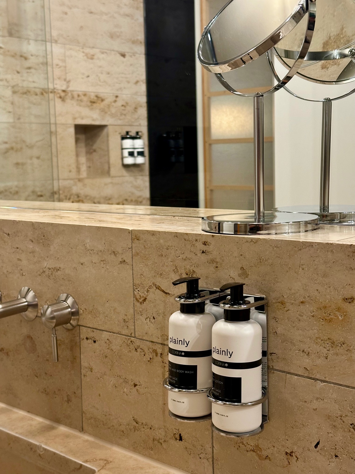 Co-branded Plainly × Cortiina bottles mounted on the bathroom wall at Cortiina Hotel, Munich